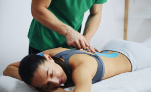 doctor-helps-woman-by-shoulder-treatment-with-Kinesio-tape