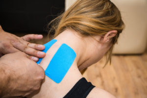 personal-trainer-applying-kinesio-tape-on-womans-wellnest